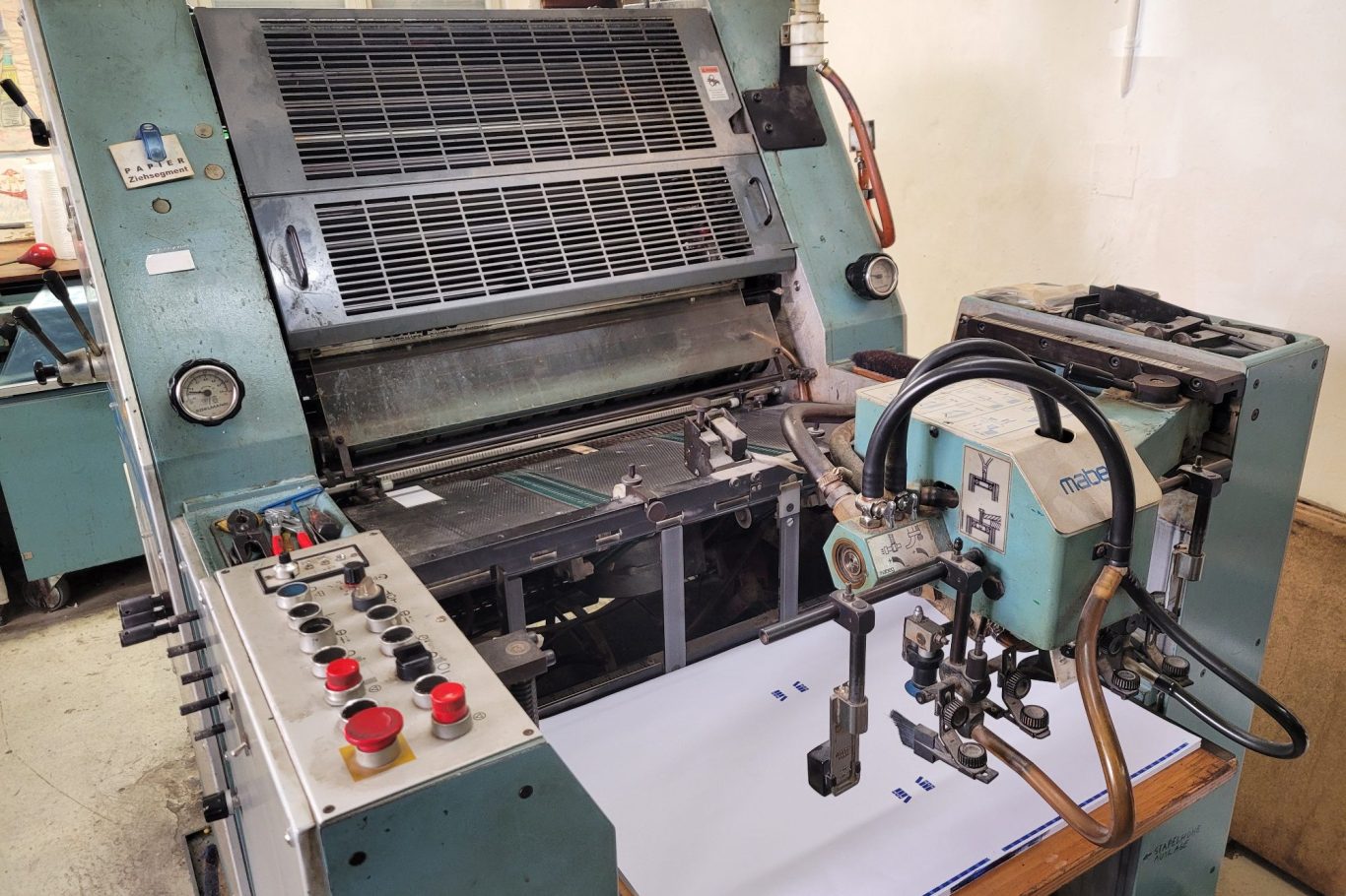 Offsetdruckmaschine Maschinenbedienungsbereich mit Steuerungselementen und Druckmechanismus.